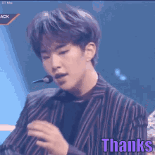 a man in a striped suit is singing into a microphone and the word thanks is written on the bottom of the image .