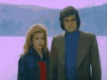 a man and a woman are standing next to each other in front of a body of water