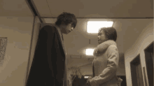 a man and a woman are standing next to each other in a hallway with chinese characters on the wall