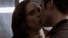 a man and a woman are kissing in front of a window in a dark room .