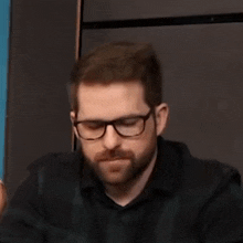 a man with a beard wearing glasses and a plaid shirt