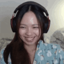 a woman wearing headphones is smiling while sitting in front of a computer screen .