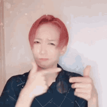 a man with red hair is making a funny face and pointing at his face .