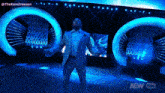 a man in a suit is standing on a stage with a aew logo in the background
