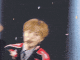 a blurry picture of a man wearing a red and black jacket and tie