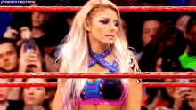 a woman is standing in a wrestling ring looking at the camera .