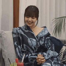 a woman in a blue robe is sitting on a couch