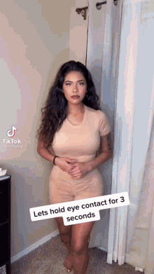 a woman is standing in a room with a caption that says " lets hold eye contact for 3 seconds " .