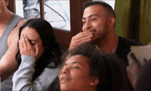 a man covering his mouth with his hand while a woman covers her face