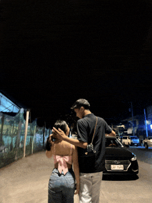 a man standing next to a woman with a license plate that says lkf 7798