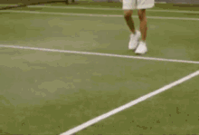 a man in a white shirt and shorts is walking on a tennis court .