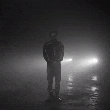 a man in a black jacket is standing in a dark room