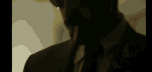 a man in a suit and tie is standing in a dark room .