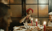 a man in a red hat is laughing while sitting at a table with other people