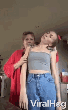 two women are standing next to each other in a living room . one of the women is holding the other 's arm .
