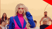 a woman in a blue and pink suit is standing in front of a crowd of people .