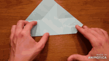 a person folding a piece of paper with the words made in animotica on the bottom right
