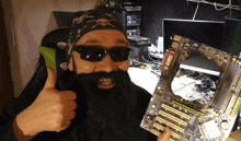 a man with a beard and sunglasses holds up a motherboard