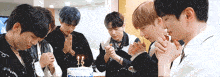 a group of young men are praying in front of a birthday cake with the number 15 on it