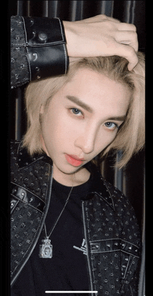 a young man with blonde hair is wearing a black jacket