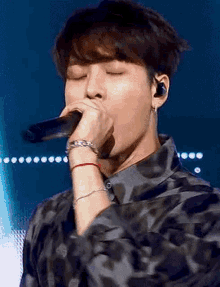 a young man is singing into a microphone on a stage .