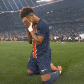 a soccer player covering his face with his hands in a stadium