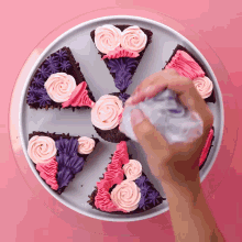 a person frosting a brownie with pink and purple frosting