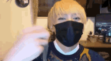 a man with blonde hair is wearing a black mask and a sweater .