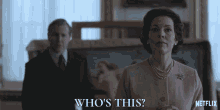 a woman in a pink jacket stands in front of a man and says who 's this