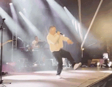 a man is singing into a microphone while dancing on stage
