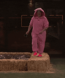 a person in a pig costume is jumping over hay bales