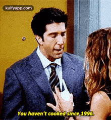 a man in a suit and tie is talking to a woman who is holding a piece of paper .