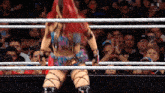 a woman in a wrestling ring with a crowd behind her and a sign that says win live