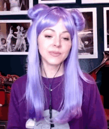 a woman wearing a purple wig and headphones is standing in front of a wall of pictures .