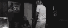 a man in a white shirt is standing in a dark room with two other men .