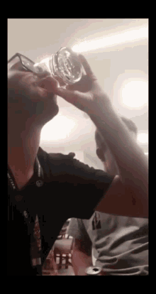 a man drinking from a glass with a lanyard around his neck that says ' toyota '