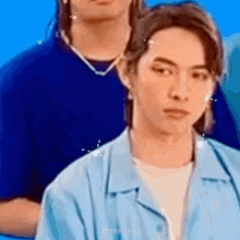 a man in a blue shirt is standing in front of another man in a blue shirt .