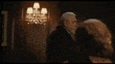 a man in a suit is talking to a woman in a dark room and says the law is people .