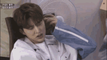 a young man is sitting in a chair with his hand on his head .