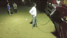 a man is standing in the dirt with a hose attached to his pants .