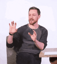 a man with a beard is sitting at a table with his hands out