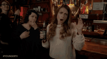 a woman in a white sweater holds a bottle of beer in her hand