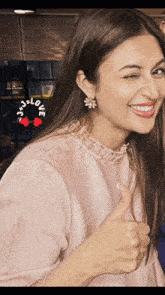a woman is smiling and giving a thumbs up with a sticker that says love