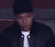 a man wearing a baseball cap and a black jacket is sitting on a couch .