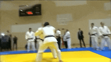 a judo match is going on in a gym with a scoreboard in the background