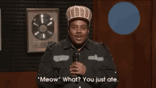 a man in a hat is speaking into a microphone and says meow what you just ate .