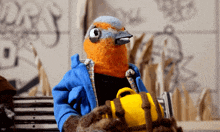 a stuffed bird in a blue jacket holds a yellow bag