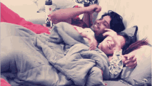 a man and a woman are laying on a bed under a blanket with a water bottle in the background that has the letter a