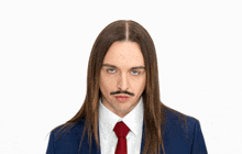 a man with long hair is wearing a blue suit and red tie
