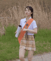 a girl in a white shirt and plaid skirt is running on a road